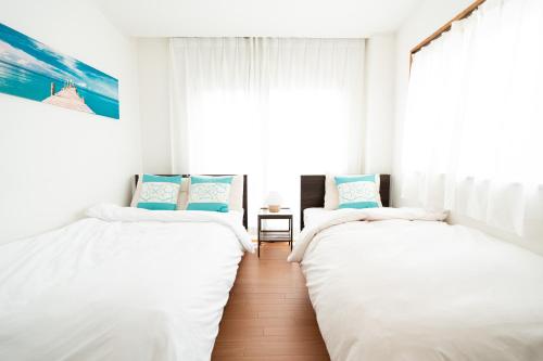 two beds in a white room with a window at Yotsugi House 3rd Floor - Prime Location Near Asakusa and Skytree in Tokyo