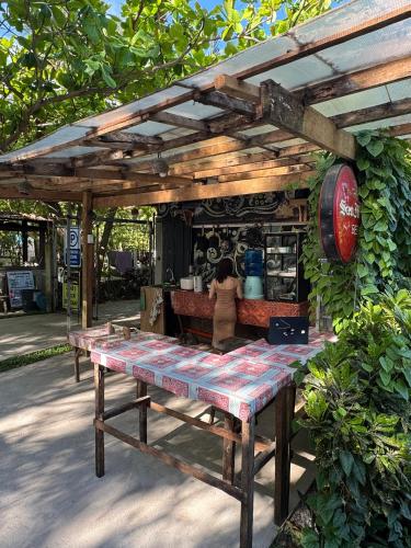 ein Picknicktisch unter einer Holzpergola in der Unterkunft ShakaBrah Beachfront Hostel in General Luna
