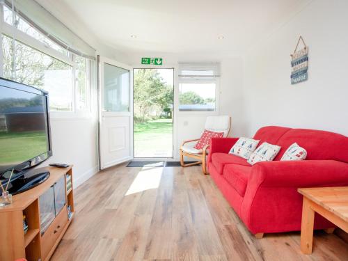 a living room with a red couch and a tv at Lodge 133 - Uk43196 in Saint Merryn
