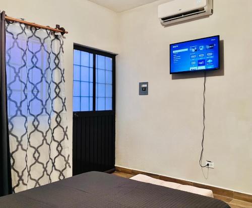 ein Zimmer mit einem Bett und einem Fernseher an der Wand in der Unterkunft Casa Mayaka in La Paz