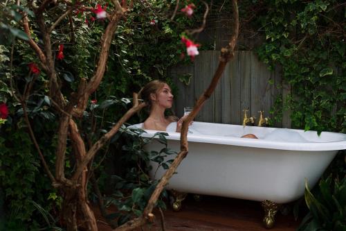 a woman sitting in a bath tub in a garden at Whimsy Cottage, Beachside retreat, Outdoor bath in Kingston Beach
