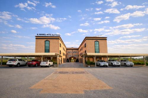 a building with cars parked in a parking lot at Al Nakheel Hotel Apartments in Ras al Khaimah
