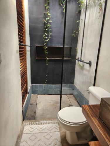 a bathroom with a toilet and plants on the wall at Mango Soul in El Zonte