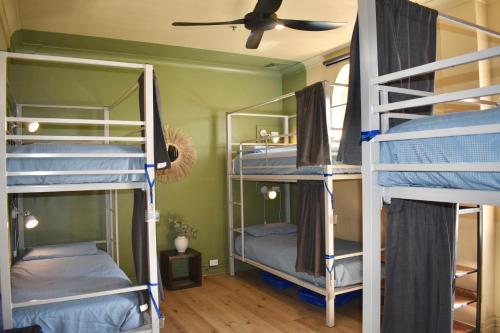 a room with three bunk beds and a ceiling fan at Mad Monkey Hostel Coogee Beach in Sydney