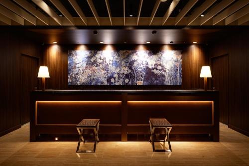 two chairs in front of a bar with a painting at Hotel Forza Nagasaki in Nagasaki
