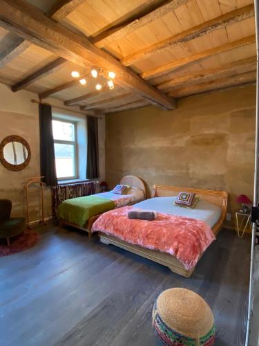 two beds in a room with wooden ceilings at Gîte La Cure in Noduwez