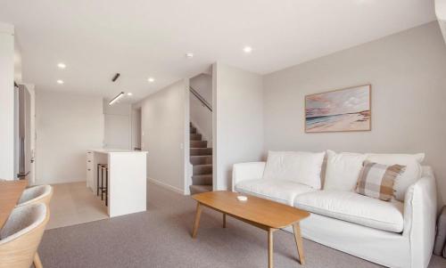 a living room with a white couch and a table at Waihi Beach Oasis - Apartment B1 in Waihi Beach