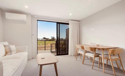 a living room with a table and a couch at Waihi Beach Oasis - Apartment B1 in Waihi Beach