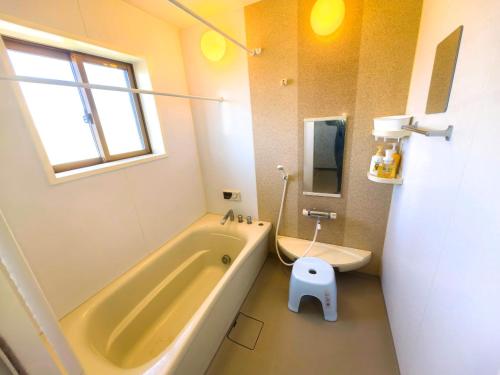 a bathroom with a tub and a toilet in it at 温泉郡宿 in Toon