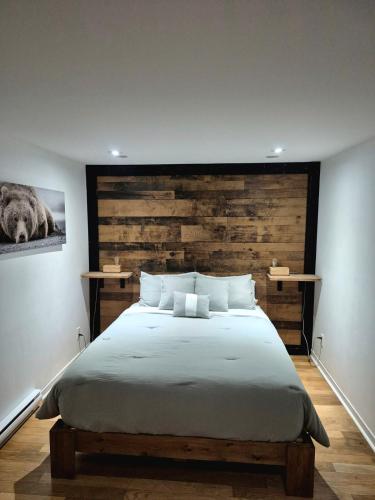 a bedroom with a large bed with a wooden headboard at Loft La Pause Orford in Magog-Orford