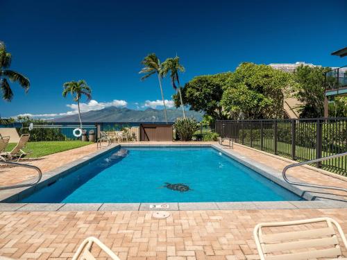 a swimming pool with blue water and palm trees at Spacious 2BR Oceanfront Loft - Unit C17 condo in Lahaina