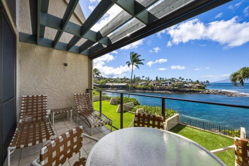 a balcony with a table and chairs and a view of the ocean at Spacious 2BR Oceanfront Loft - Unit C17 condo in Lahaina