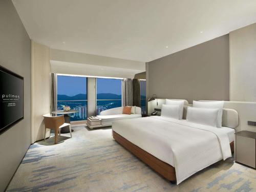 a bedroom with a large white bed and a large window at Pullman Shenzhen North in Shenzhen