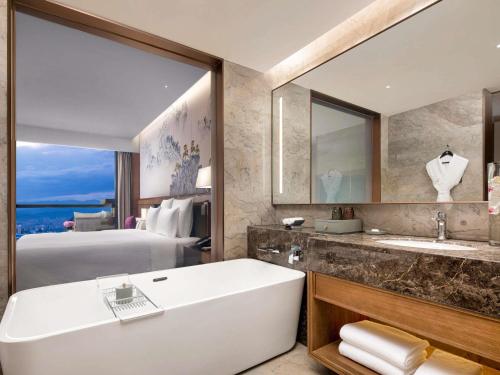 a bathroom with a tub and a bedroom with a bed at Pullman Yuxi in Yuxi