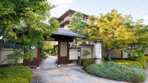 a japanese garden with a gate and trees at Kadensho, Arashiyama Onsen, Kyoto - Reopening on 2026 in Kyoto