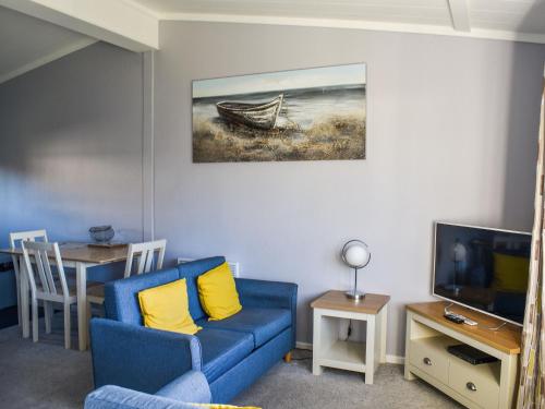 a living room with a blue couch and a tv at Alula Lodge in Lowestoft