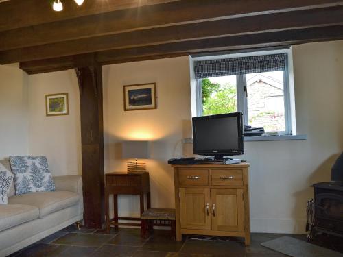a living room with a tv and a couch and a window at The Pigsty Cottage E2783 in Oswestry