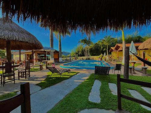 a resort with a swimming pool with chairs and umbrellas at Pousada Pé da Serra in Lindóia