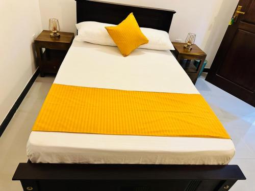 a bed with a yellow blanket on top of it at KOKO Villa in Kochchikade