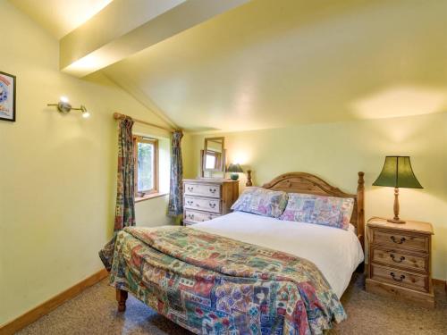a bedroom with a bed and a dresser and a lamp at Bilbrook- Ukc4913 in Timberscombe