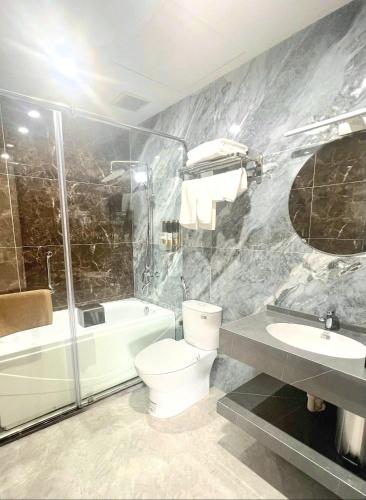 a bathroom with a toilet and a tub and a sink at Khách sạn đẹp Hà Nội - Royal Louis Hotel in Dại Mõ