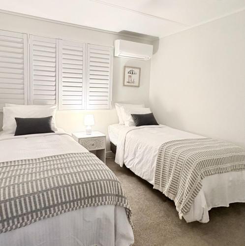 two beds in a room with white walls and windows at Rainbow House in Rainbow Beach