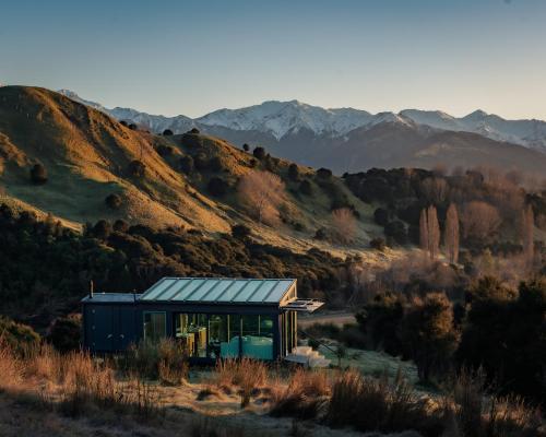 a house on a hill with mountains in the background at Kahutara PurePod in Kaikoura