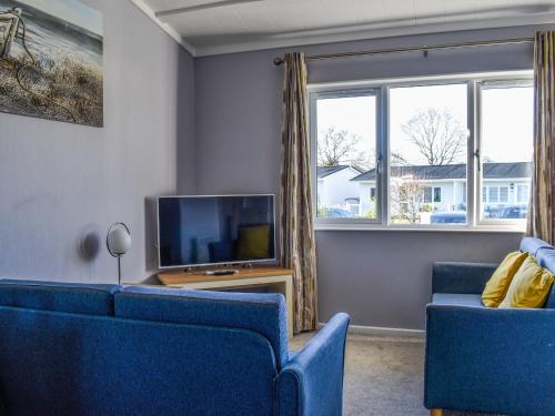 a living room with two blue chairs and a tv at Alula Lodge in Lowestoft
