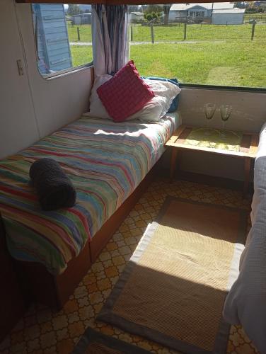 a small bed in a room with a window at Cosy Caravan in Takaka