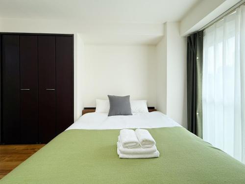 a bedroom with a bed with two towels on it at サムティ扇町 in Osaka