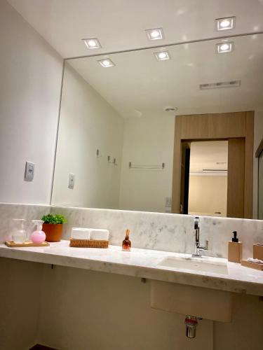 a bathroom with a sink and a large mirror at Azure Aesse Hospitality Marista in Goiânia