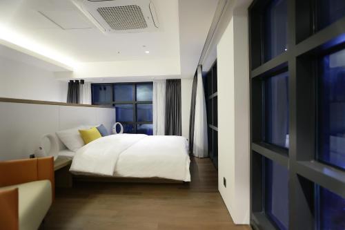 ein Schlafzimmer mit einem weißen Bett und einem Fenster in der Unterkunft 루나스카이돔 구 스페이스앤무드 in Busan
