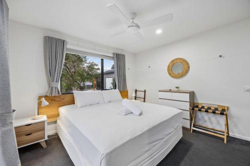 a bedroom with a large white bed and a window at Roses Creek Chalet B in Crackenback