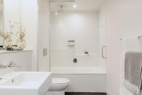 a white bathroom with a toilet and a shower at Punthill Williamstown in Williamstown
