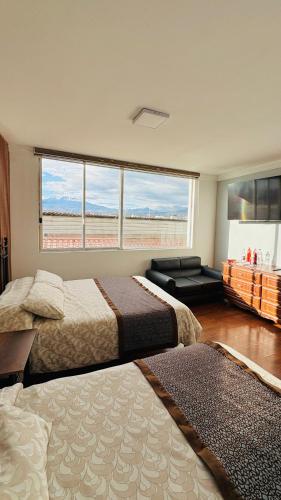 a bedroom with two beds and a large window at Hotel El Altar in Riobamba