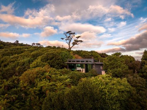 a house on top of a hill with a tree at Hananui PurePod in Stewart Island