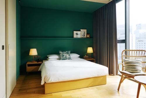 a green bedroom with a bed and a chair at La Casa hotel Gwangmyeong in Gwangmyeong