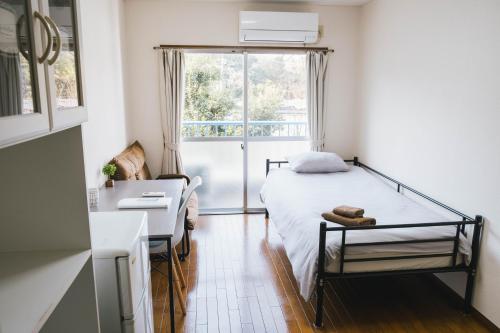 a bedroom with a bed and a desk and a window at Osaka English House in Hirakata