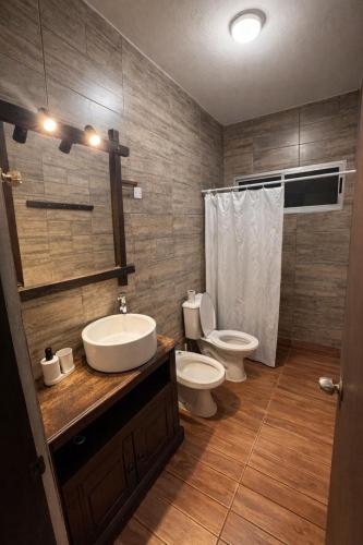 a bathroom with a sink and a toilet and a mirror at Refugio del bosque - Casa con jacuzzi descanso en Piriapolis in Piriápolis