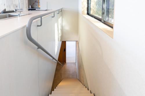 a staircase in a house with white walls and wooden floors at Villa CASK Setouchi in Mitoyo
