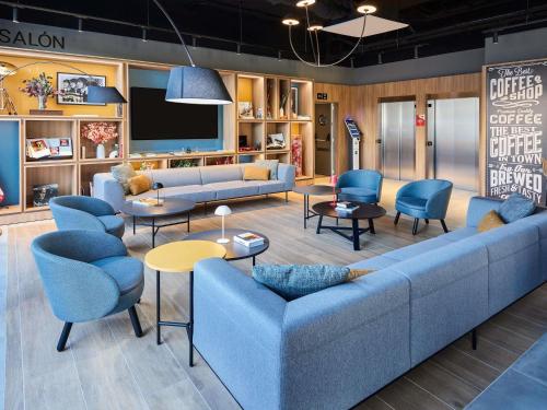 a living room with couches and chairs and a tv at ibis Madrid Norte Las Tablas in Madrid