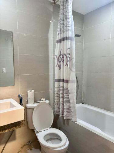 a bathroom with a toilet and a shower curtain at Mactan Newtown Studio Type with Balcony in Punta Engaño