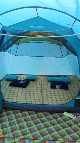 a bed in a blue tent with pillows on it at Tenda Premium Pantai Madasari in Bulakbenda