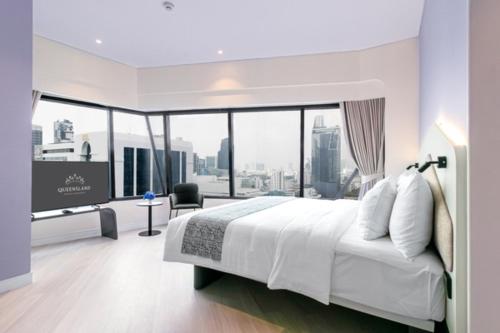 a hotel room with a bed and a flat screen tv at Queensland Hotel Bangkok in Bangkok