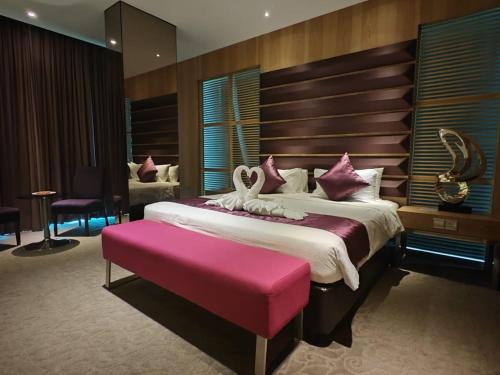 a bedroom with a large bed with a pink seat at Greens Hotel & Suites in Bintulu