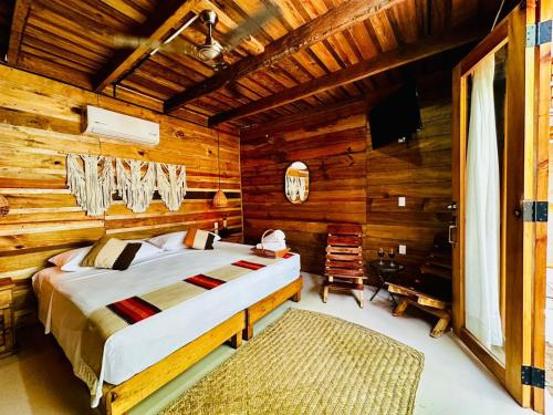 a bedroom with a bed in a log cabin at Straw hat suites La punta in Santa María Colotepec