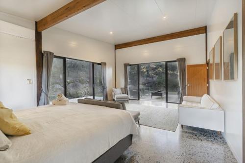 a bedroom with a large bed and large windows at Old Bales Serene Hinterland Oasis in Myocum