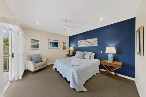a bedroom with a bed and a blue wall at Tidal Haven in Noosaville