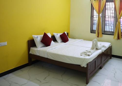 a bed in a room with yellow walls and windows at Lakshmi Palace Near Madurai Bus Stand in Madurai