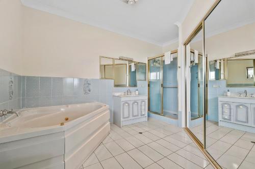 a bathroom with a tub and two sinks at Beachfront - Opposite Boat Ramp in Golden Beach